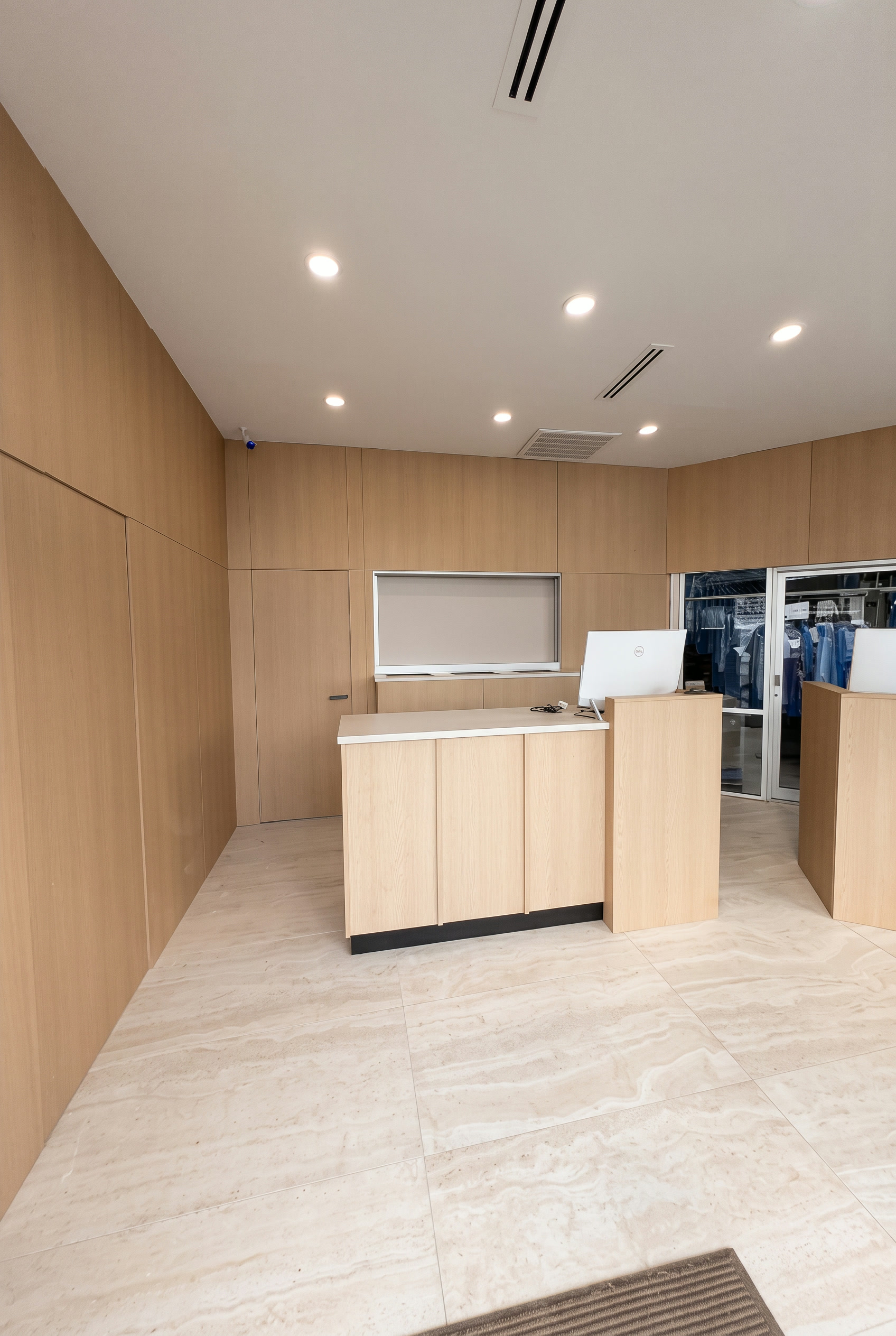 Inside the newly remodeled Pro Cleaners store on West Gray, with light wood counters and garment racks behind glass